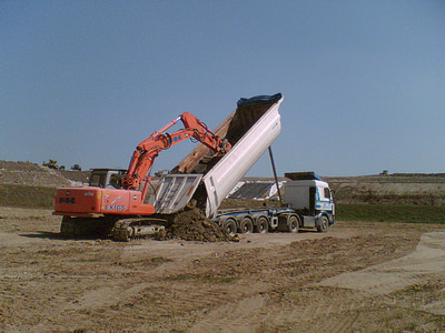 Foto di un nostro escavatore che scarica un camion impiegato per il trasporto terra